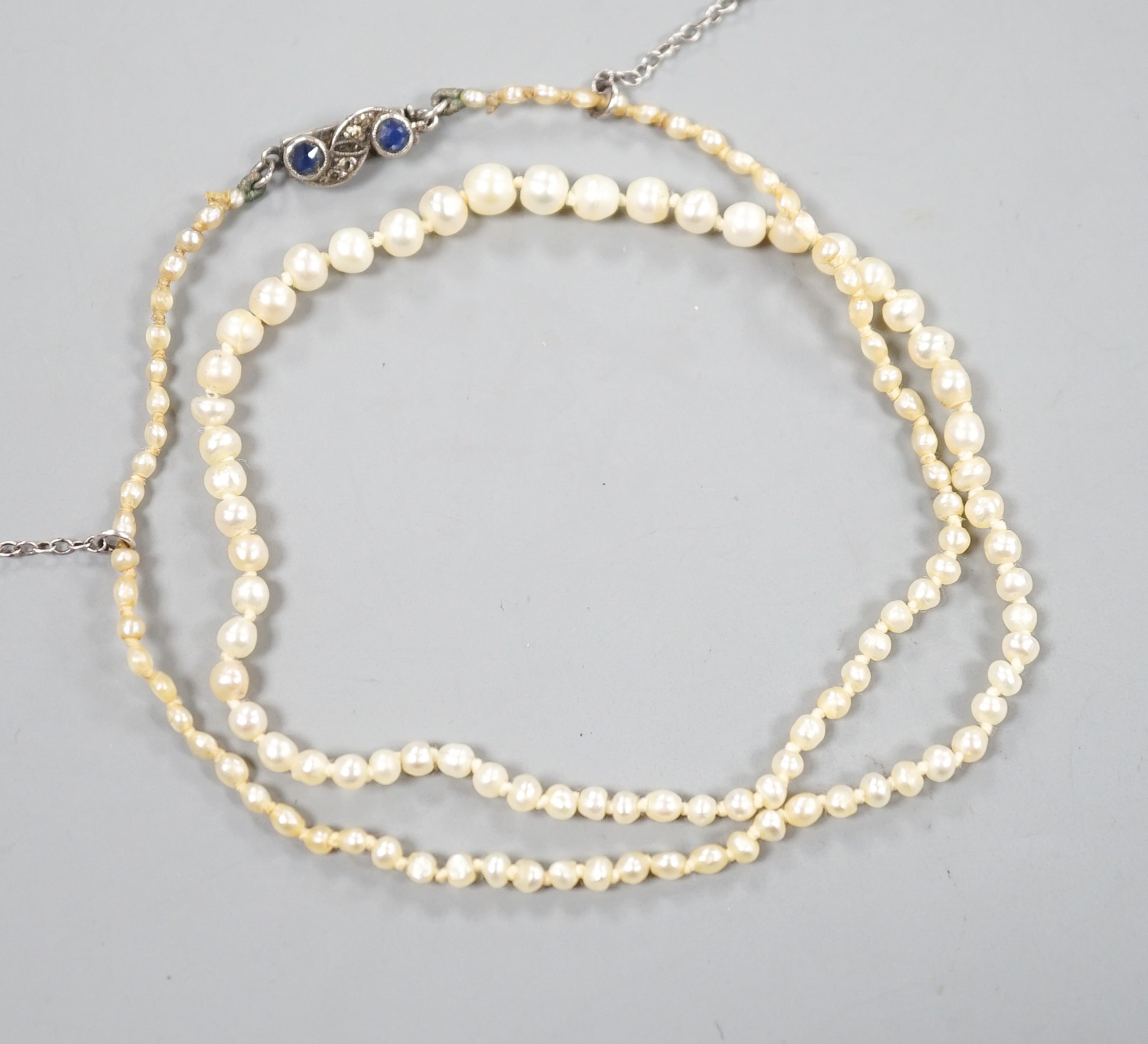 An Edwardian single strand graduated natural saltwater pearl necklace, with sapphire and diamond chip set clasp, 38cm, gross weight 5.7 grams, with accompanying Gem & Pearl Laboratory report dated 1/2/2022.